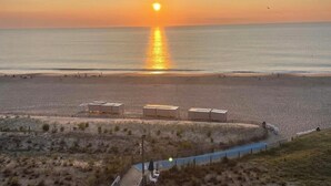A beach with a sunset, a boardwalk, and beach huts. - Sea Colony Oceanfront 1 Bedroom Condo Beautiful View Sept 21 -25 Super Special  (Bethany Beach)