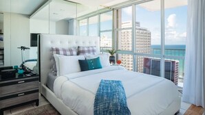 A modern hotel room with a large bed, a nightstand, a lamp, and a view of the ocean. - Ocean View  19 floor  STUDIO Apt In the Condado Area NO PARKING (San Juan)