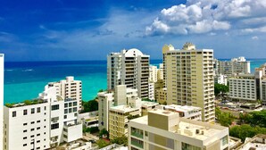 A coastal cityscape with high-rise buildings, a clear blue sky, and the ocean in the background. - Ocean View  19 floor  STUDIO Apt In the Condado Area NO PARKING (San Juan)