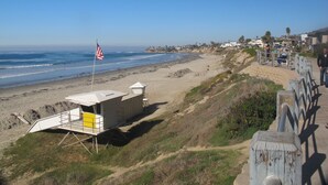 A lifeguard station with a flag, a beach, and a residential area in the background. - Newly refreshed  Beach Apartment..Steps to the sand! (San Diego)