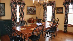 A dining room with a wooden table, six chairs, floral curtains, and a chandelier. - Charming 5 bedroom Easton Point colonial with honeymoon suite on 3rd floor (Middletown)