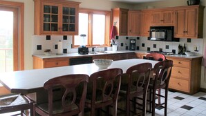 A kitchen with wooden cabinets, a large island with chairs, a microwave, and a sink. - Charming 5 bedroom Easton Point colonial with honeymoon suite on 3rd floor (Middletown)