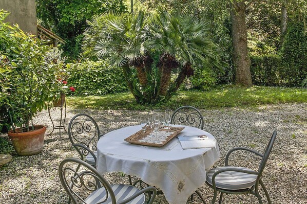 An outdoor dining area with a round table, metal chairs, and a white tablecloth.