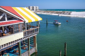 A waterfront restaurant with outdoor seating and a view of the beach and ocean.