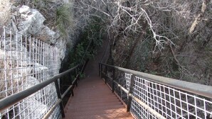 A metal staircase with metal railings, surrounded by rocky terrain and sparse vegetation.