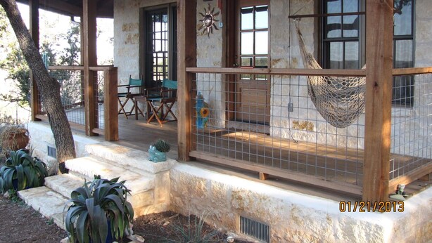 A rustic building with a porch, wooden chairs, and a hammock.