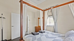 Un dormitorio con una cama con dosel, un aparador de madera y una ventana con cortinas.