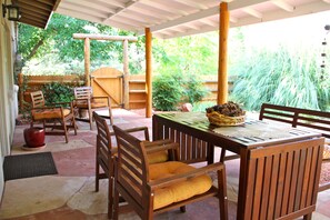 Eine überdachte Terrasse mit Holzmöbeln und einem für das Essen gedeckten Tisch.