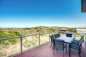 A balcony with a table and chairs, overlooking a hilly landscape.