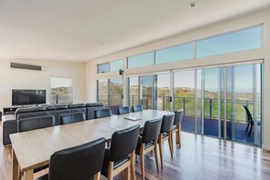 A spacious conference room with a long table and chairs, a television, and large windows offering a view of the landscape.