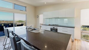 Una cocina moderna con una isla grande, armarios blancos y vistas al paisaje.