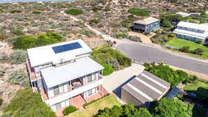 Una casa moderna de dos pisos con un panel solar, un garaje y vista al océano.
