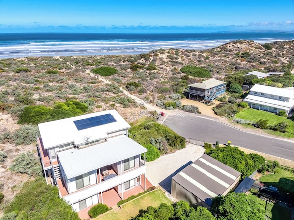 A modern two-story house with a solar panel, a garage, and a view of the ocean.