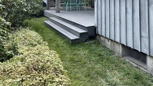 A wooden deck with outdoor seating and steps leading to a covered area. - Prud'homme Cottage: bright, private architectural cottage on Mitchell Cove (Bernard)