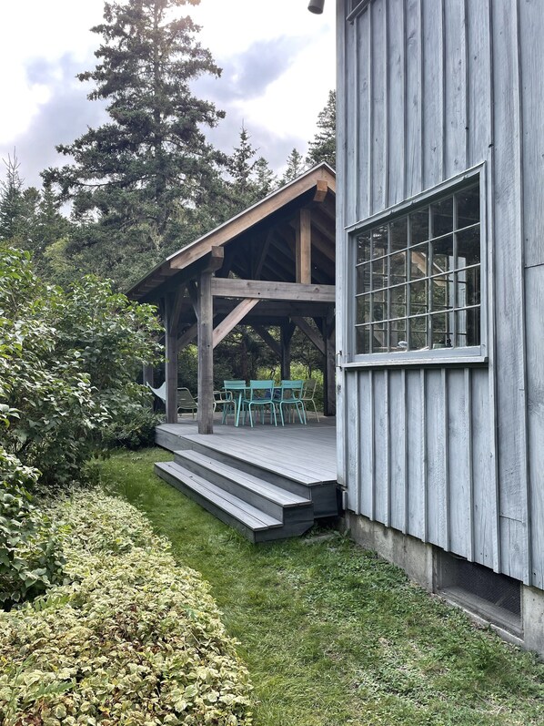 A wooden deck with outdoor seating and steps leading to a covered area.