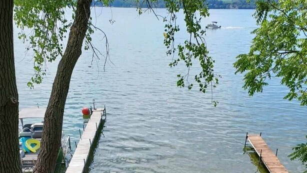 A wooden deck with outdoor seating, a view of the water, and a dock.