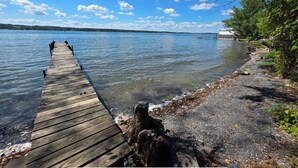 A wooden pier extending into calm water, surrounded by trees and a clear sky.