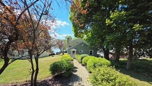 A house with a paved pathway leading to the front door, surrounded by well-maintained bushes and trees.