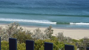 Une plage avec des vagues et de la végétation au premier plan.