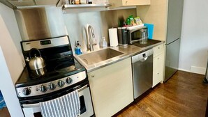 A compact kitchen with a stove, sink, and dishwasher.
