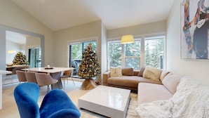 Un salon moderne avec une grande fenêtre, un sapin de Noël, un canapé et un coin repas.