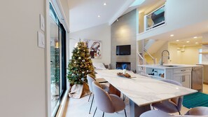 Une cuisine moderne dotée d’un four encastré, un coin repas avec une table en marbre et un sapin de Noël.