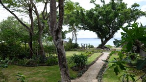 Um jardim com um caminho de cascalho que leva a um gazebo à beira da água.