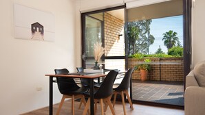 En matplats med ett bord, stolar och utsikt över utomhusmiljön genom en skjutdörr i glas.