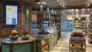 A bakery counter with fresh bread and pastries, a refrigerated section labeled 'SIP, REFRESH', and a menu board on the wall.