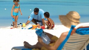 A beach scene with people playing and relaxing.