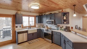 A modern kitchen with wooden cabinets, stainless steel appliances, and a large window. - Private Peninsula With 3,000 Feet Of Lakeshore In The Heart Of Lake Country! (Baxter)