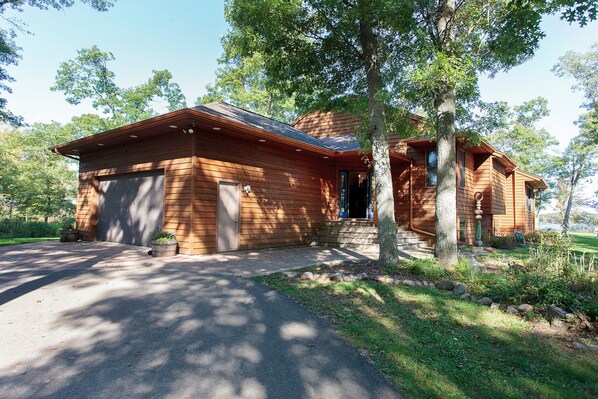 A wooden cabin with a garage, surrounded by trees and a well-maintained lawn. - Private Peninsula With 3,000 Feet Of Lakeshore In The Heart Of Lake Country! (Baxter)