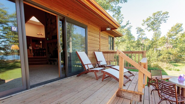A wooden deck with outdoor furniture, a dining table, and a staircase leading to a covered area. - Private Peninsula With 3,000 Feet Of Lakeshore In The Heart Of Lake Country! (Baxter)