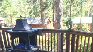 A wooden deck with a stone fire pit and a table.