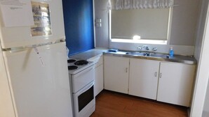 Una cocina compacta con gabinetes blancos, estufa y pileta.
