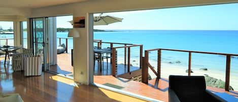 A spacious balcony with a view of the sea, furnished with chairs and a table.