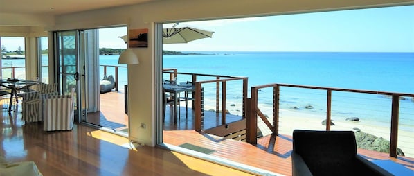 Varanda ampla com vista para o mar, equipada com cadeiras e uma mesa.