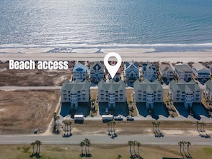 Una propiedad frente a la playa con una hilera de casas modernas, acceso directo a la playa y una vista despejada del océano.