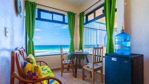 A balcony with a view of the ocean, a wooden chair with colorful cushions, a small table, and a water dispenser. - Villa Tranquila-Versatile 4 Bedroom Villa W/Rooftop Pool, Oceanfront . (Isla Mujeres)