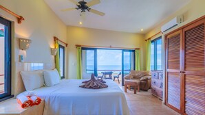 A hotel room with a bed, a chair, a table, and a view of the ocean. - Villa Tranquila-Versatile 4 Bedroom Villa W/Rooftop Pool, Oceanfront . (Isla Mujeres)