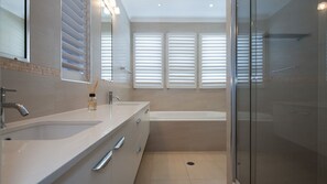 A modern bathroom with a glass shower enclosure, a bathtub, and a vanity with a mirror. - Seaside Beach House (Marcoola)