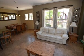 Uma sala de estar com sofá, mesa de jantar, cadeiras e mesa de centro.