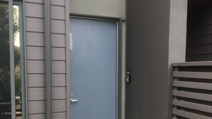 A modern building with a grey door, a small entrance with a mat, and a grey fence. - Coast at The Sands, Torquay (Torquay Surfcoast)