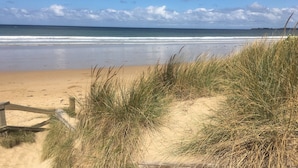 A beach with sand, grass, and a wooden fence. - Coast at The Sands, Torquay (Torquay Surfcoast)