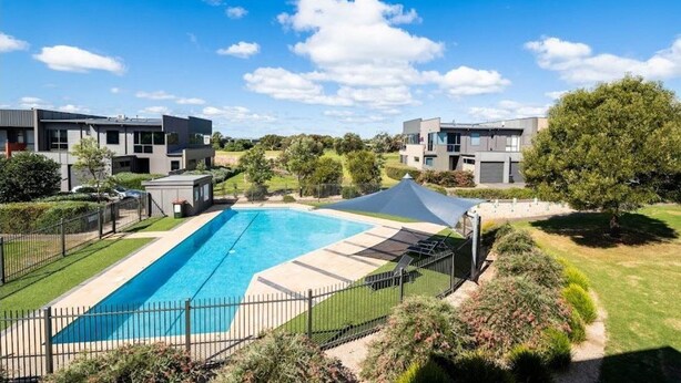 A modern residential complex with a swimming pool, surrounded by well-maintained lawns and trees. - Coast at The Sands, Torquay (Torquay Surfcoast)