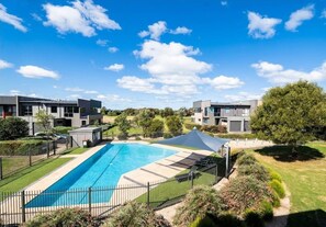 A modern residential complex with a swimming pool, surrounded by well-maintained lawns and trees. - Coast at The Sands, Torquay (Torquay Surfcoast)