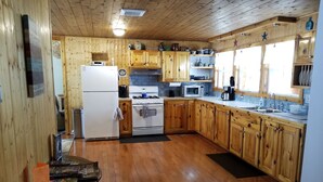 A wooden-paneled kitchen with a refrigerator, stove, microwave, and wooden cabinets. - Beautiful Black Mountain Recreational Area Vacation Rental Cheboygan, MI (Cheboygan)