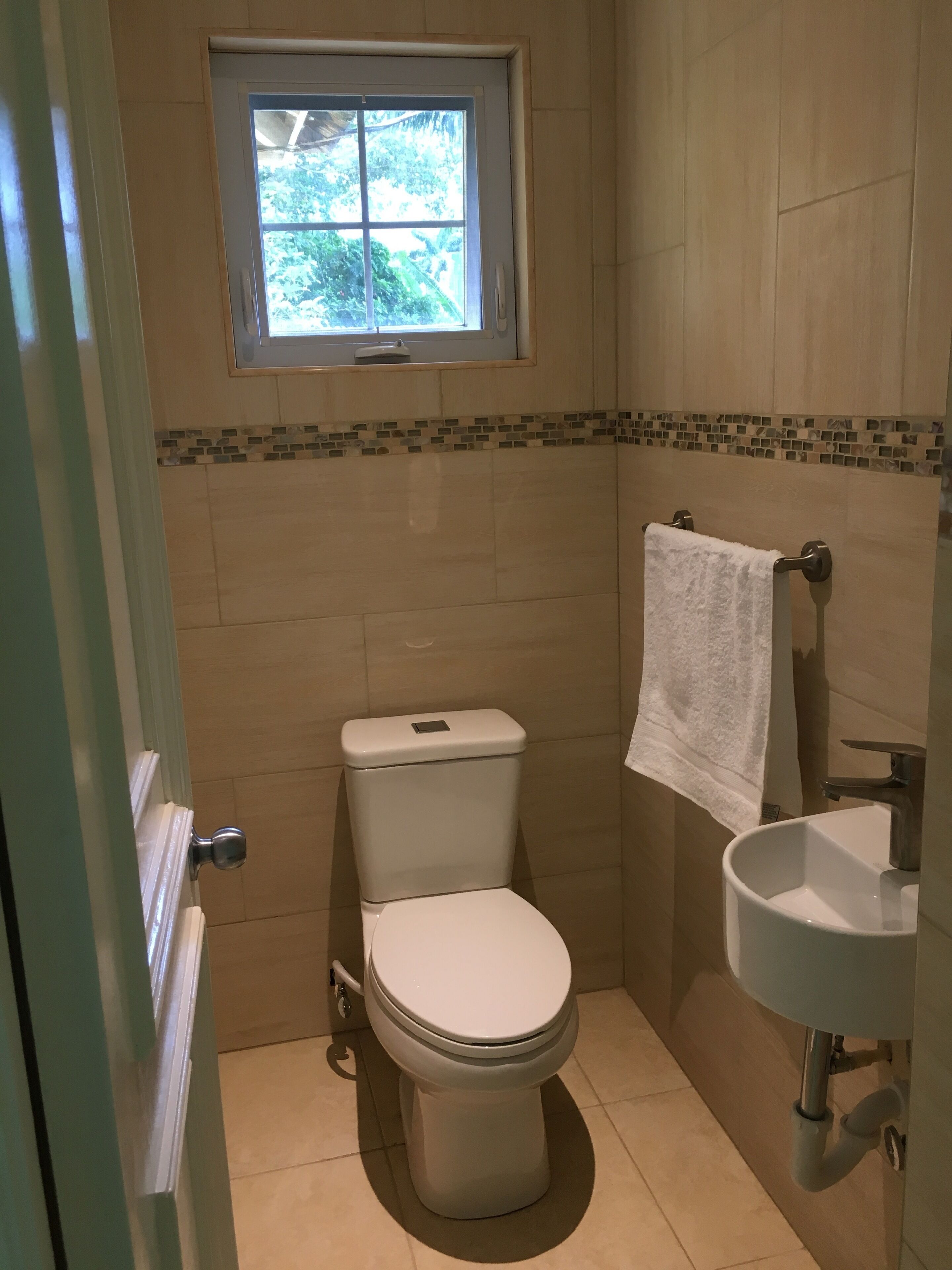 Ein kleines Badezimmer mit Toilette, Waschbecken und Fenster.