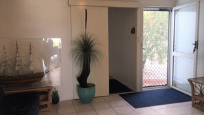 A room with a large ship model, a potted plant, a door leading outside, and a wicker chair. - 4/42 Manooka Drive - Rainbow Beach. Stunning Panoramic Views and Swimming Pool (Rainbow Beach)