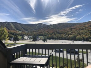 Enjoy the serene mountain views from this balcony with a table and parking lot views.